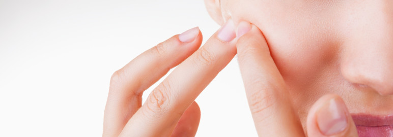 Picture of a woman pinching a spot on her face