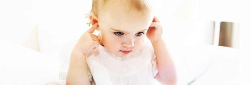 Picture of a baby girl covering her two ears in a white background.