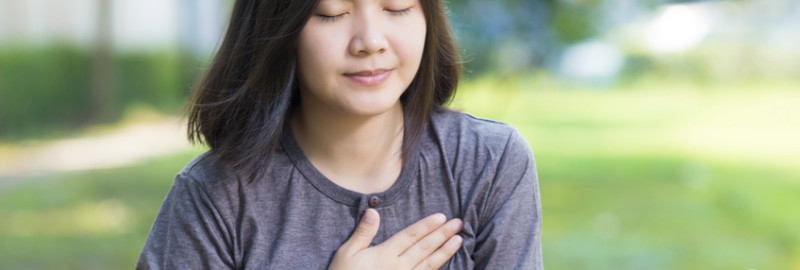 Asian lady placing her hand on her chest because sore chest pain