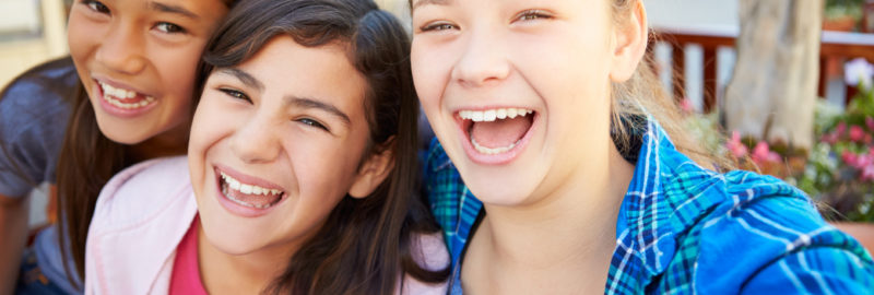 Group of girls hanging out in mall together, smiling and laughing to camera.