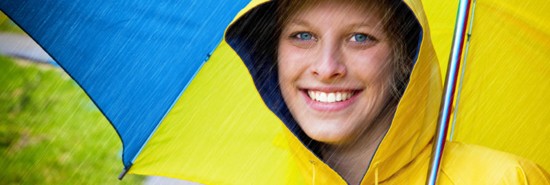 Happy woman in a yellow raincoat and umbrella.