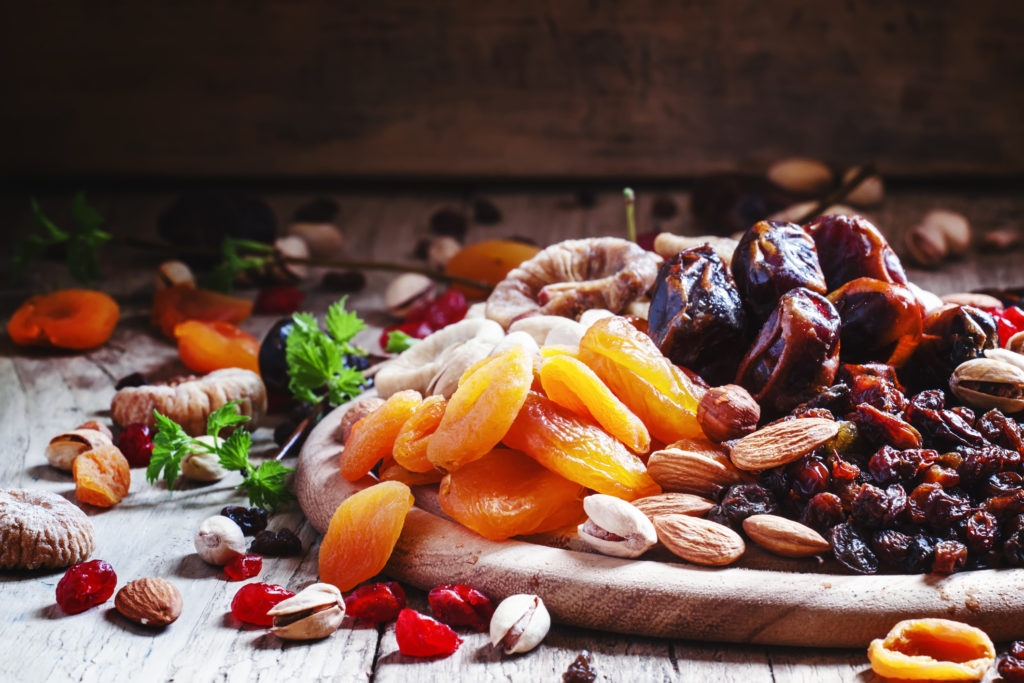 Dried apricots, dates, raisins and various nuts, vintage wooden background in a selective focus