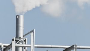 Metal factory smokestack releasing steam, gas and harmful smoke